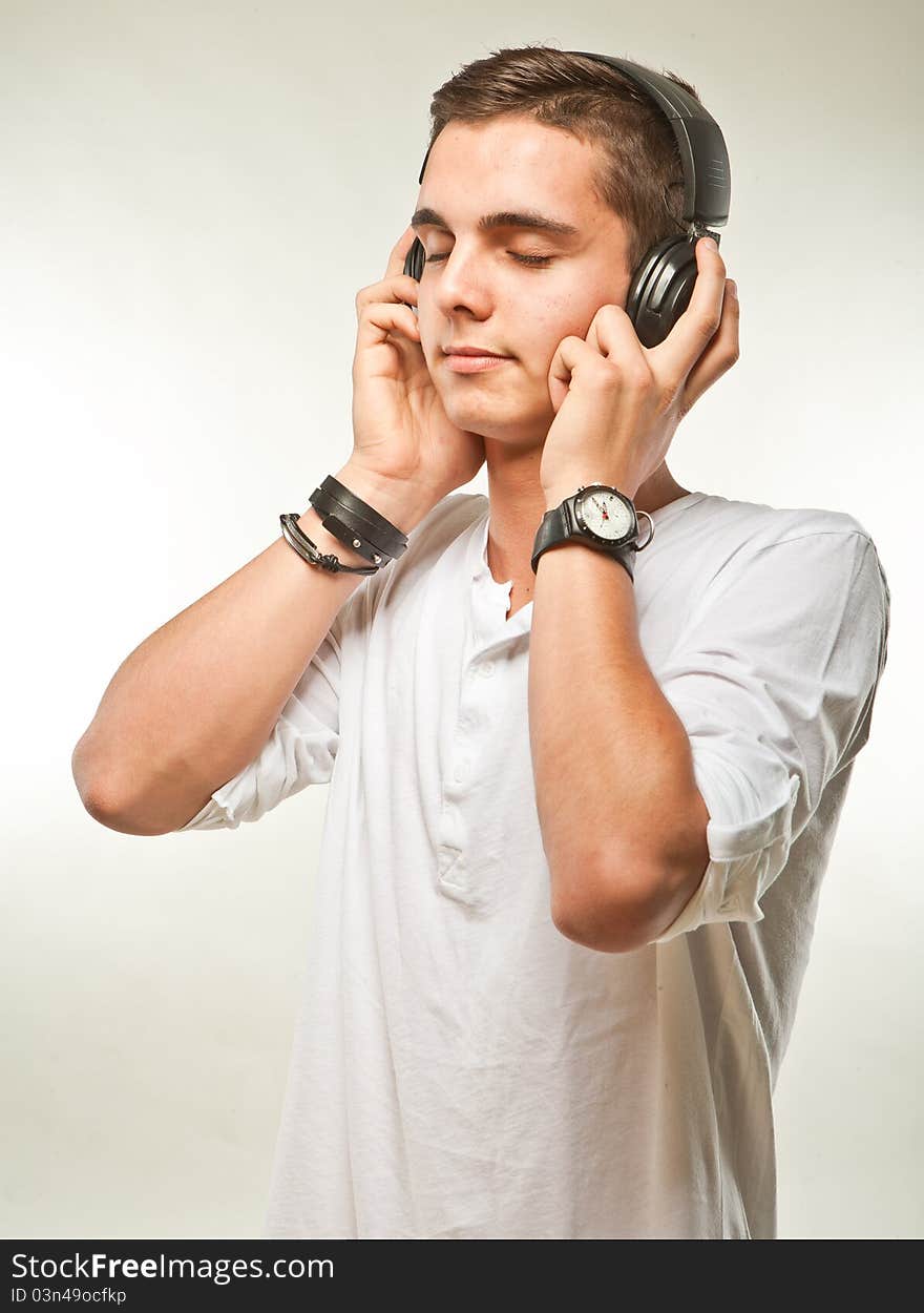 Young man listening music on his headphones. Candid picture. Young man listening music on his headphones. Candid picture.