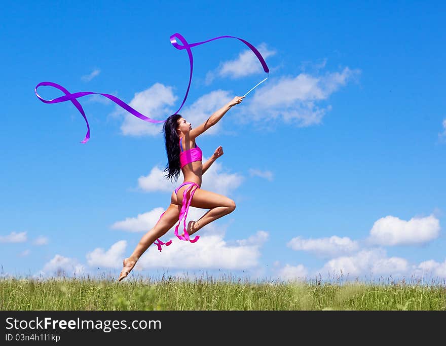 Happy jumping young woman with a ribbon outdoor on a summer day. Happy jumping young woman with a ribbon outdoor on a summer day