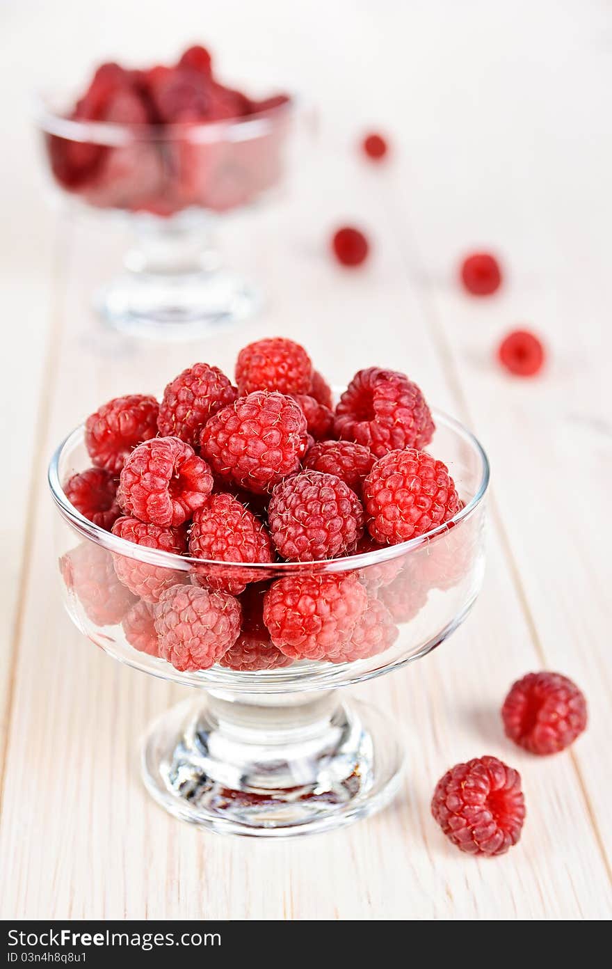 Raspberry in a small glass bowl on the light background