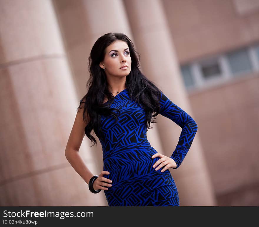 Very beautiful young brunette woman wearing a blue mini dress in the street. Very beautiful young brunette woman wearing a blue mini dress in the street