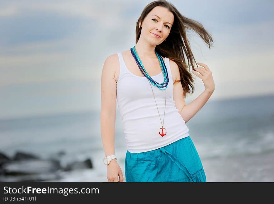 Beautiful young woman stands against ocean