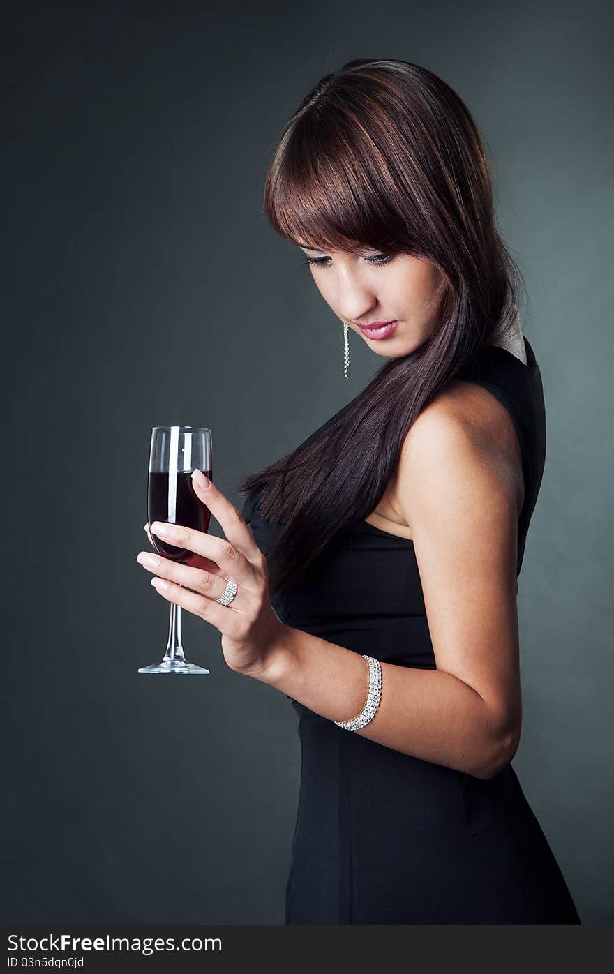 Portrait of young sexy woman wearing in the evening dress holding glass of wine