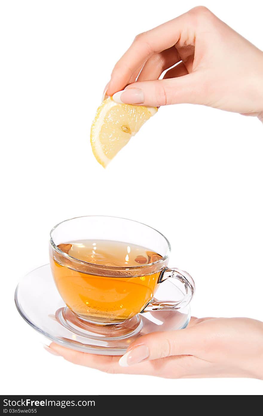 Woman hand adding lemon to tea over white