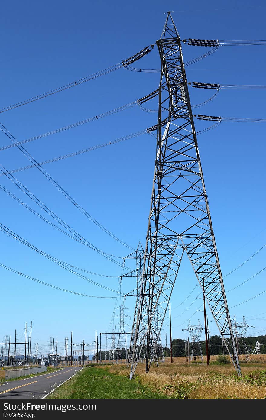 Tall towers distributing power-lines to various directions in an open field. Tall towers distributing power-lines to various directions in an open field.