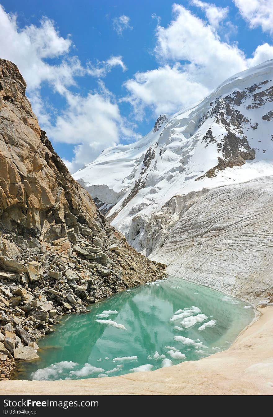 Mountain lake with ice, snow and clouds