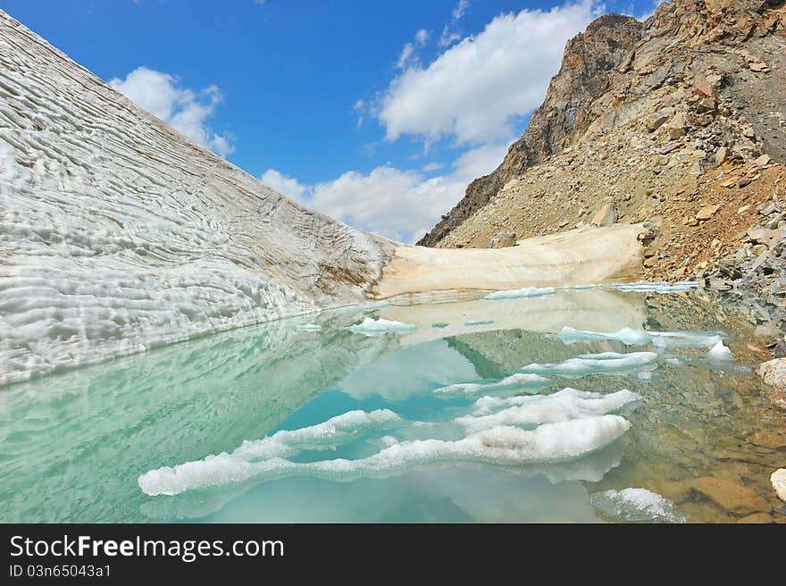 Mountain lake with ice, snow and clouds