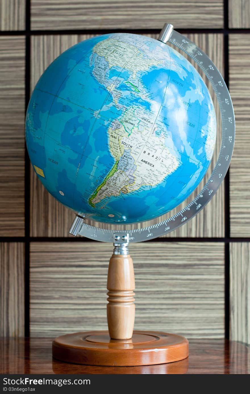 A blue earth globe on a wooden stand with latitude degree scale. A blue earth globe on a wooden stand with latitude degree scale