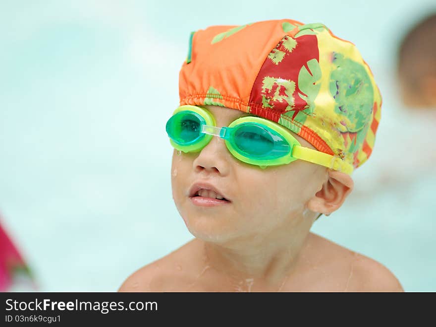 Four years old asian boy in swimming pool wearing swimming glasses.