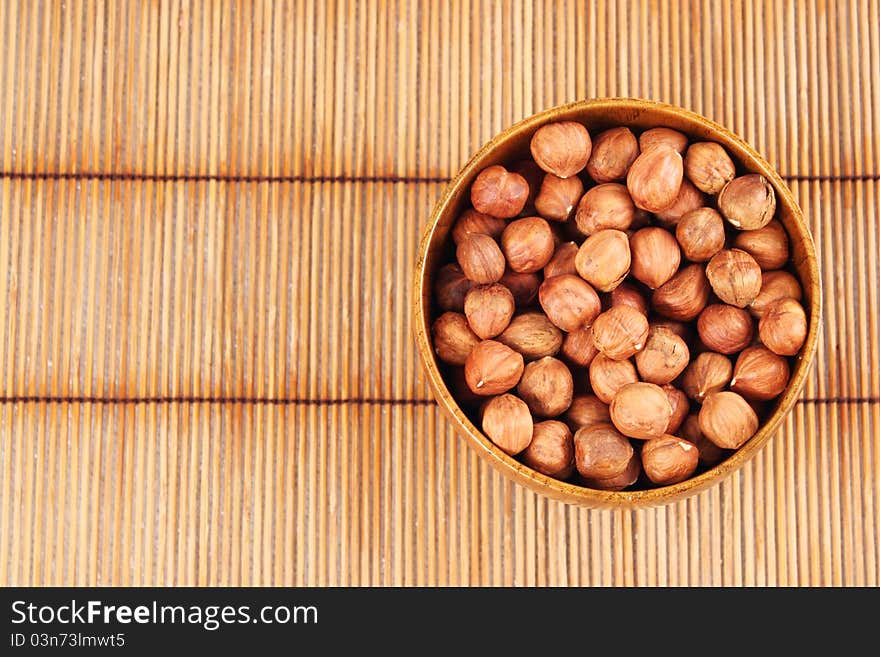 Hazelnut in a bowl on the background of a bamboo mat