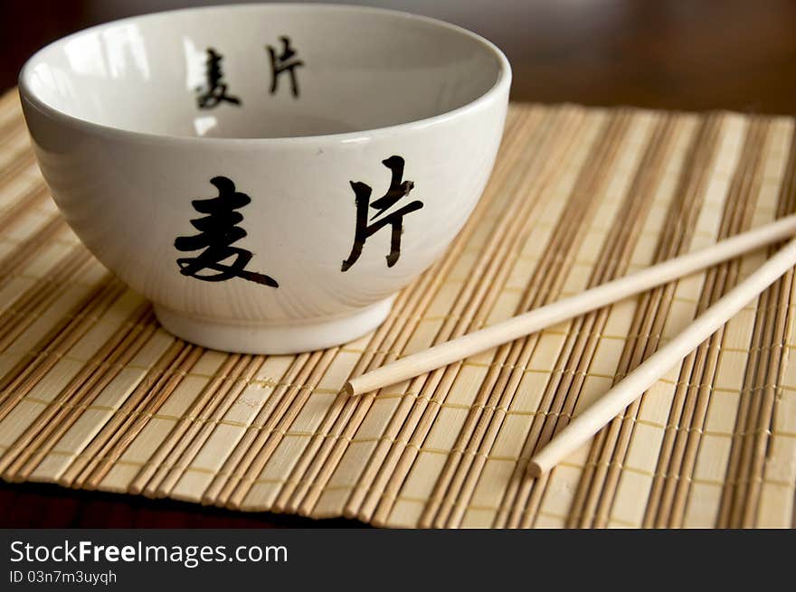 Chinese white bowl and sticks on bamboo mat. Chinese white bowl and sticks on bamboo mat