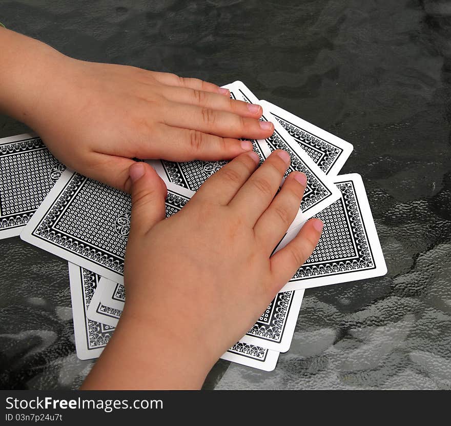 Closeup of two kid hands over a pile of playing cards. Closeup of two kid hands over a pile of playing cards