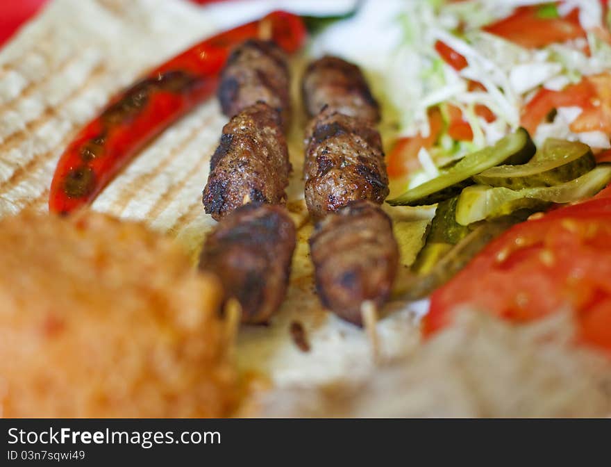 Traditional turkish shish kebab served on white plate with vegetables and lavash