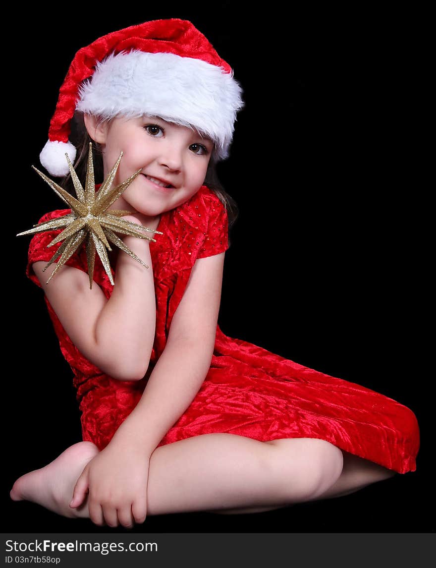 Pretty little girl in Santa hat posing with golden star. isolated on black. Pretty little girl in Santa hat posing with golden star. isolated on black