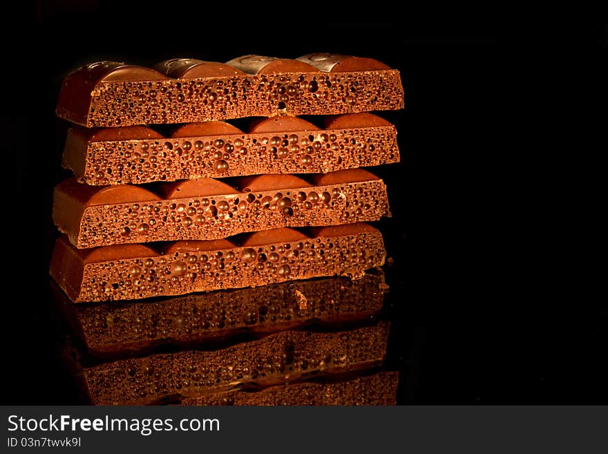 Pieces of black aerated chocolate on black background