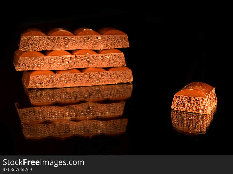 Pieces of black aerated chocolate on black background