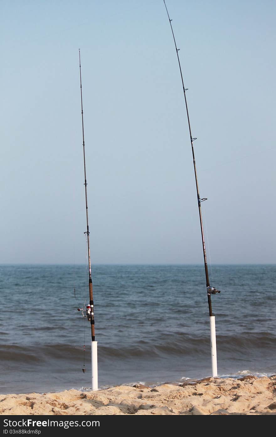 Fishing poles on the beach by the surf. Fishing poles on the beach by the surf