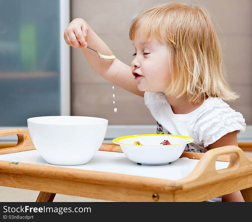 A small girl is sitting on the floor and is eating. A small girl is sitting on the floor and is eating