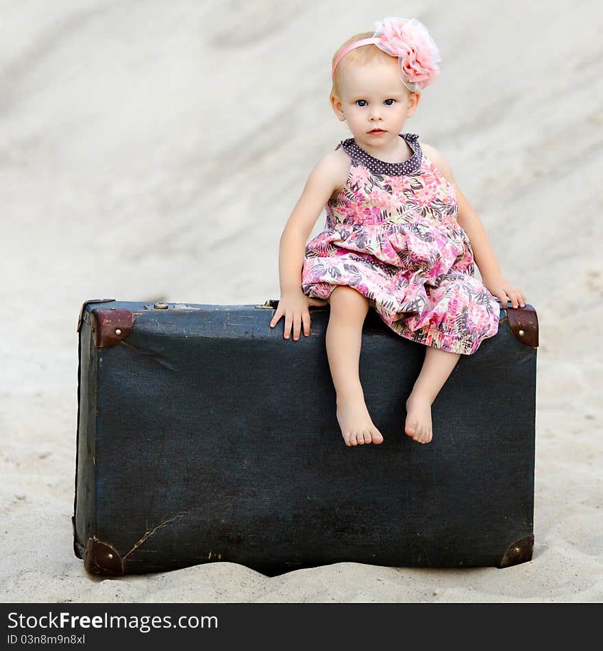 Little girl sitting on a suitcase in the desert. Little girl sitting on a suitcase in the desert