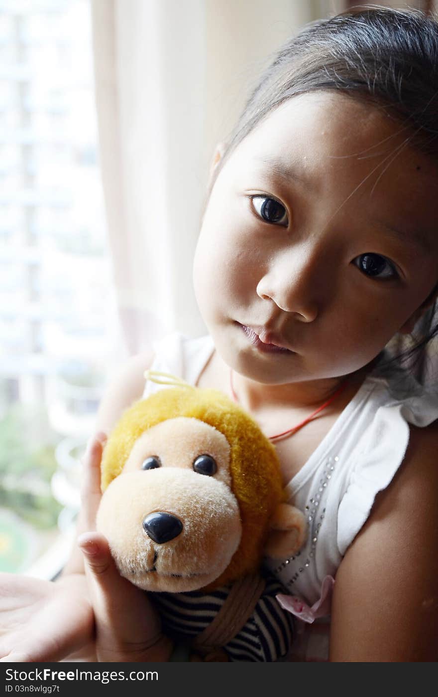 Bright picture of adorable chinese girl Holding the Toy Monkey near the windows. Bright picture of adorable chinese girl Holding the Toy Monkey near the windows