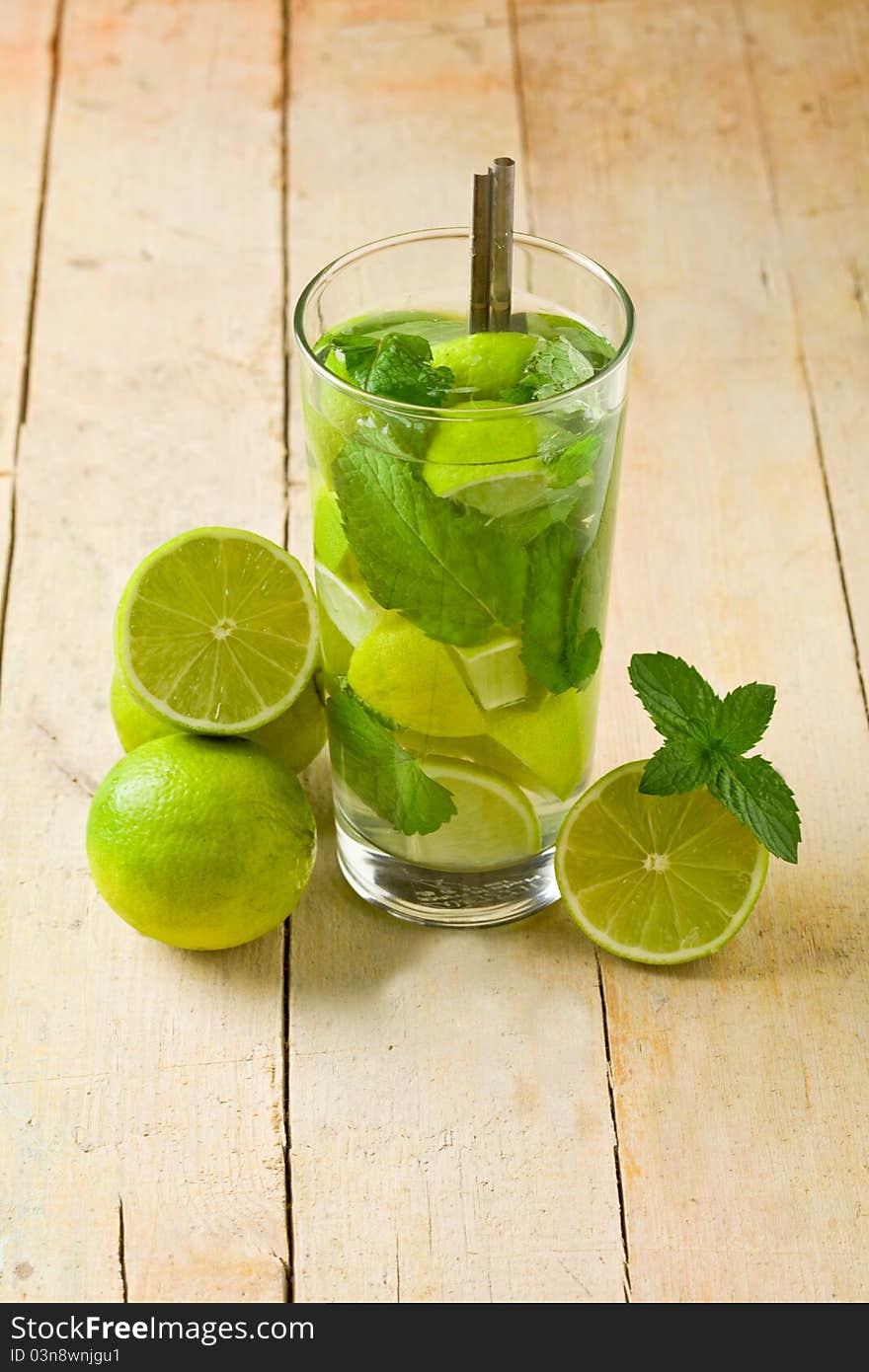 Photo of delicious mojito cocktail with cuttd lime on wooden table