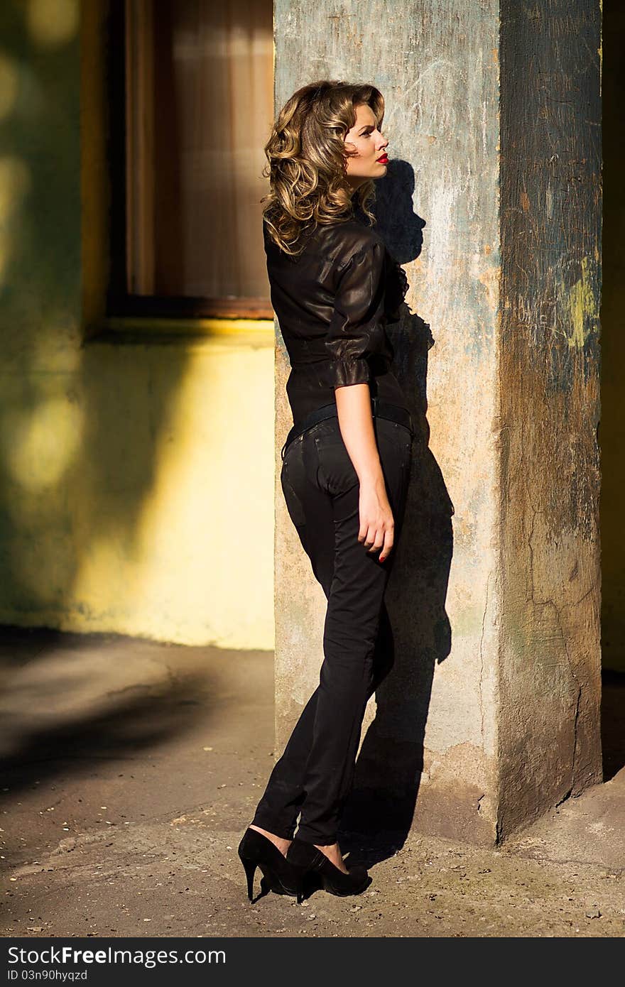 Portrait of a beautiful woman posing at the city street in sunset back light