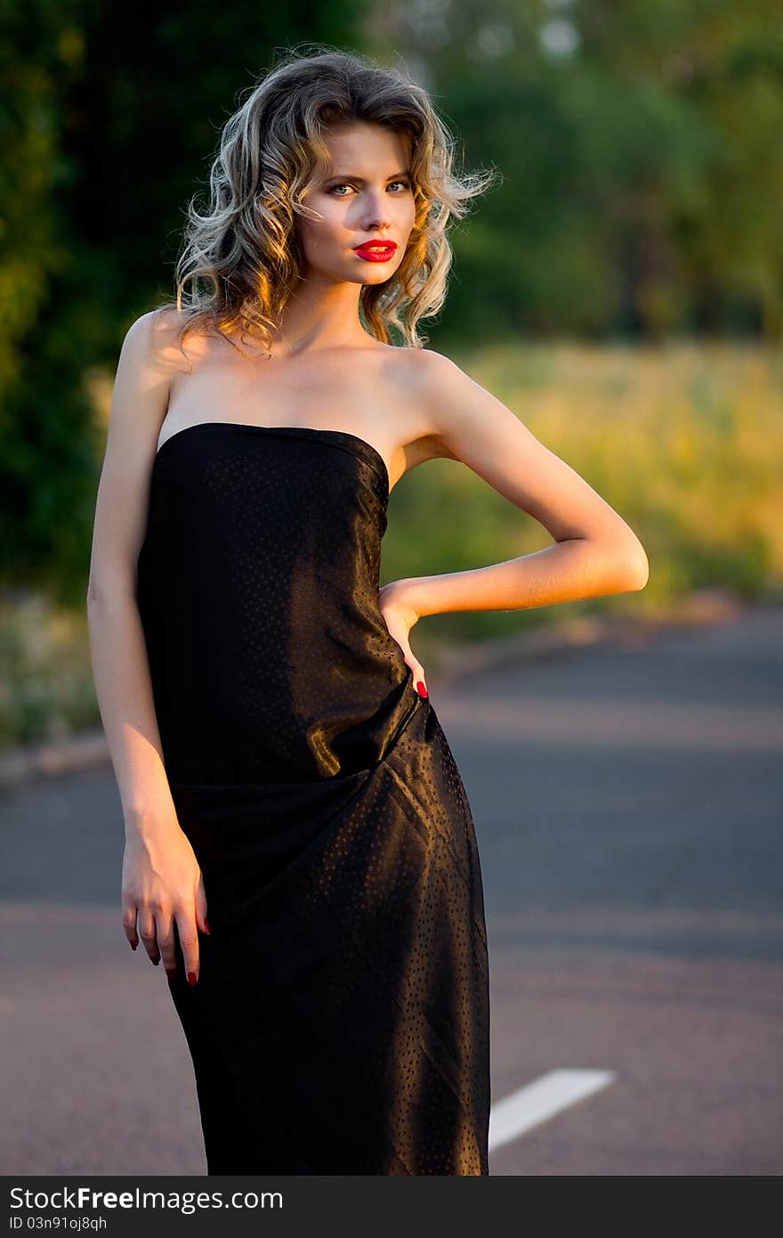 Portrait of a beautiful woman posing at the city street in sunset back light