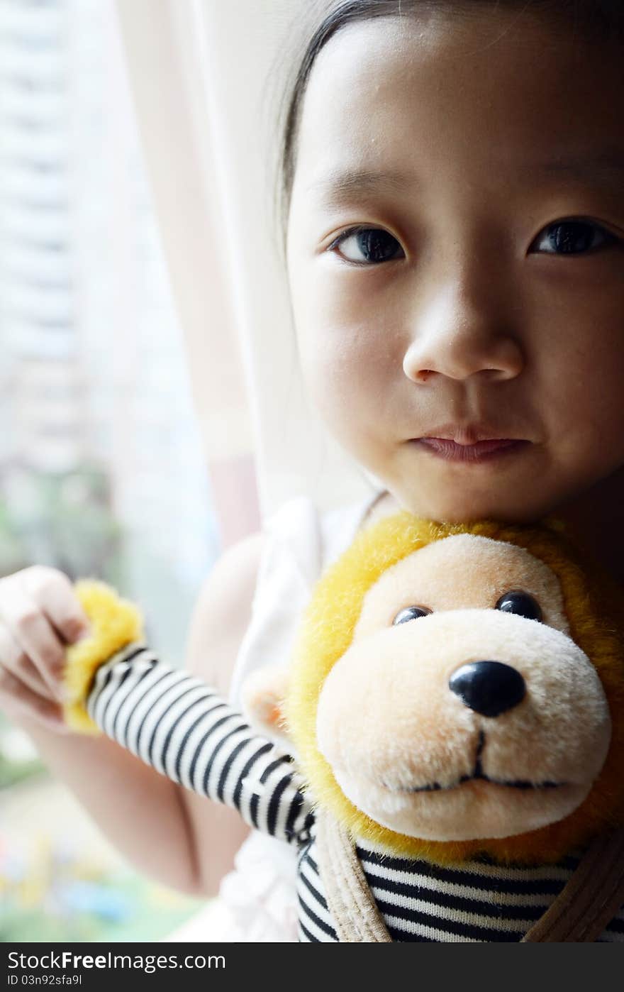 Bright picture of adorable chinese girl Holding the Toy Monkey near the windows. Bright picture of adorable chinese girl Holding the Toy Monkey near the windows