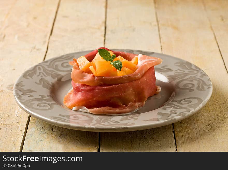 Photo of delicious sliced bacon with melon inside on wooden table. Photo of delicious sliced bacon with melon inside on wooden table