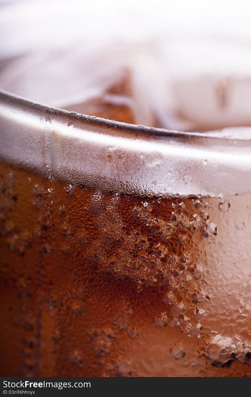 Cold cola in a glass with ice cubes. Macro view. Cold cola in a glass with ice cubes. Macro view.