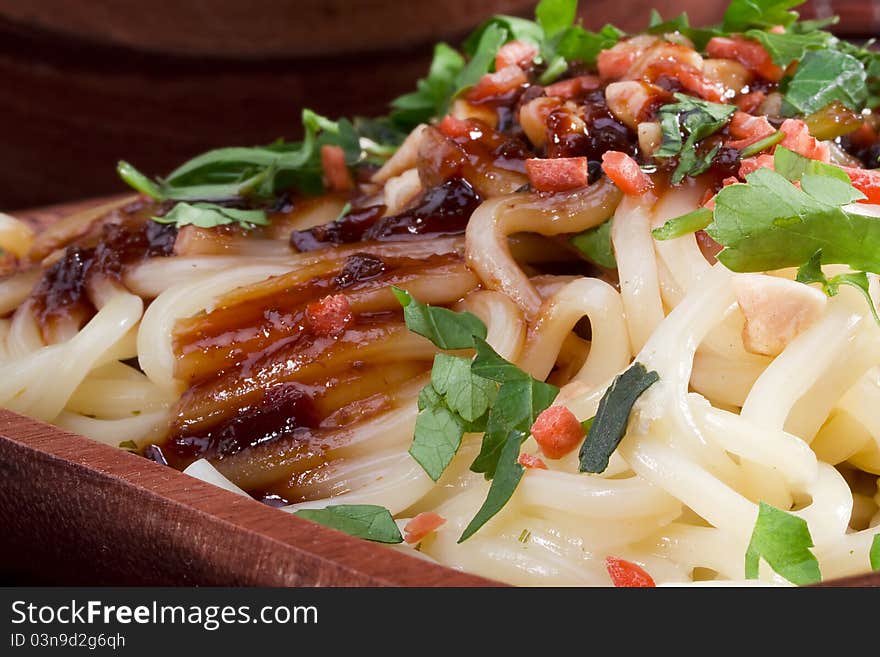 Freshly prepared Asian noodles on a brown wooden plate.