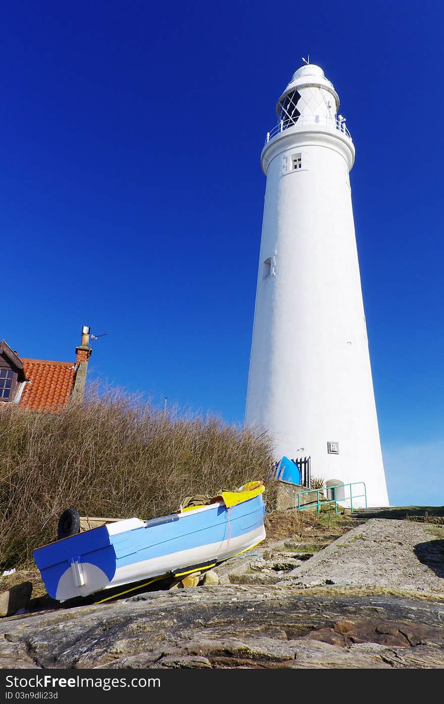 Close up of lighthouse and blue boat matching blue sky. Close up of lighthouse and blue boat matching blue sky