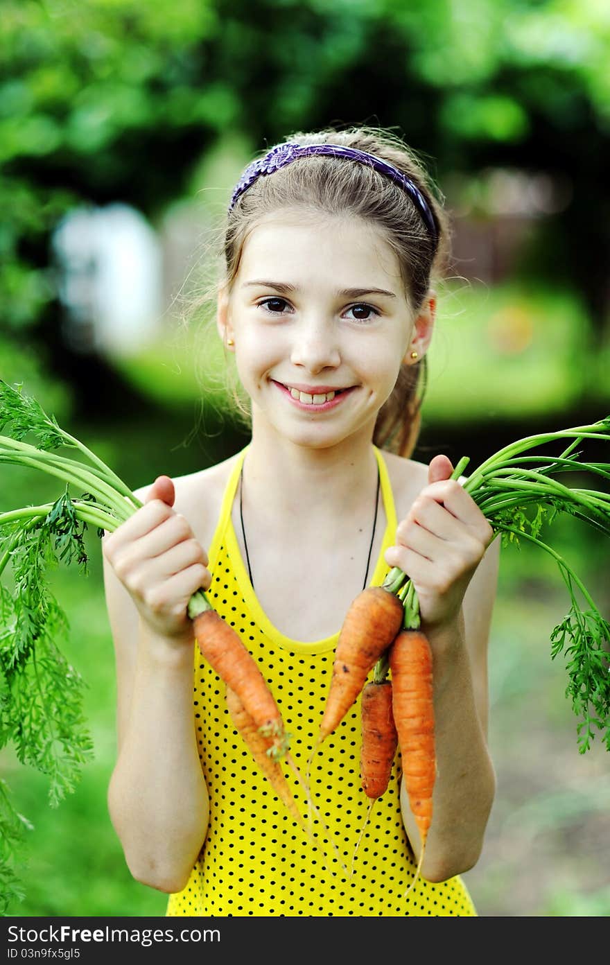 An image of a little girl with orange carrots. An image of a little girl with orange carrots