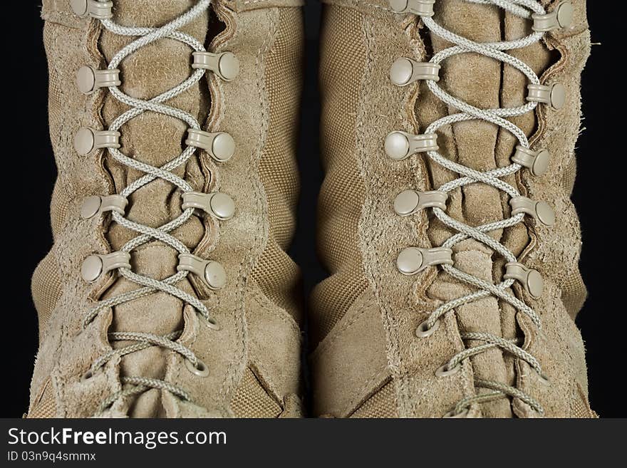 Close-up of tan leather Army combat boot laces on black background. Close-up of tan leather Army combat boot laces on black background.