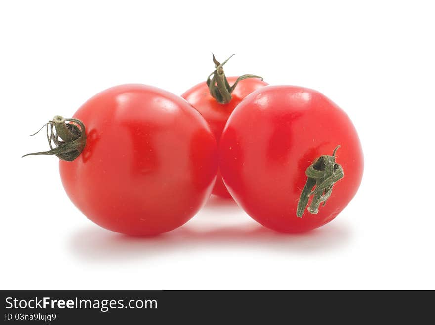 Cherry tomatoes with green tails, lie group. Their three. On a white background. Cherry tomatoes with green tails, lie group. Their three. On a white background.