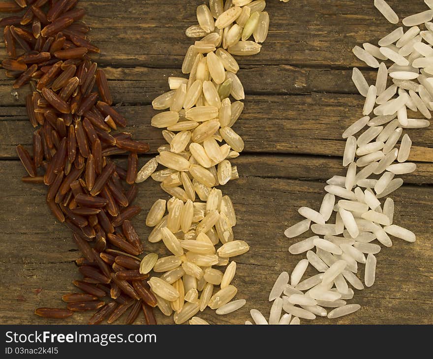 Tree types of rice over wooden background