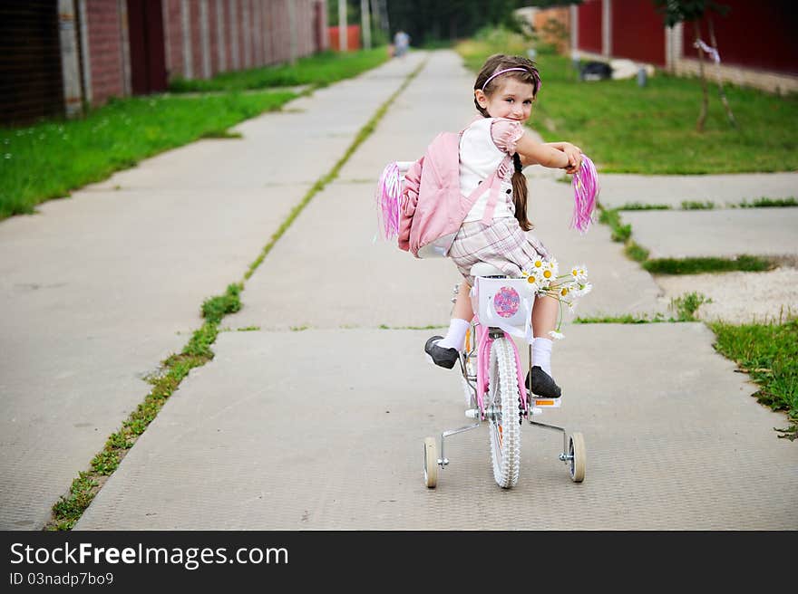 Young School Girl With Pink Bagpack On A Bicycle