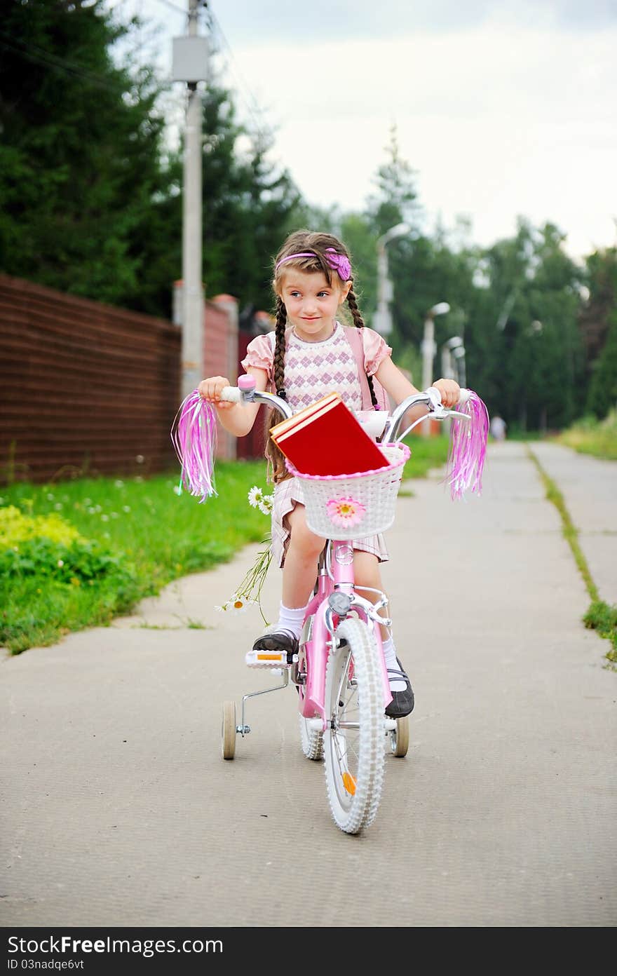 Young school girl rides her pink bicycle