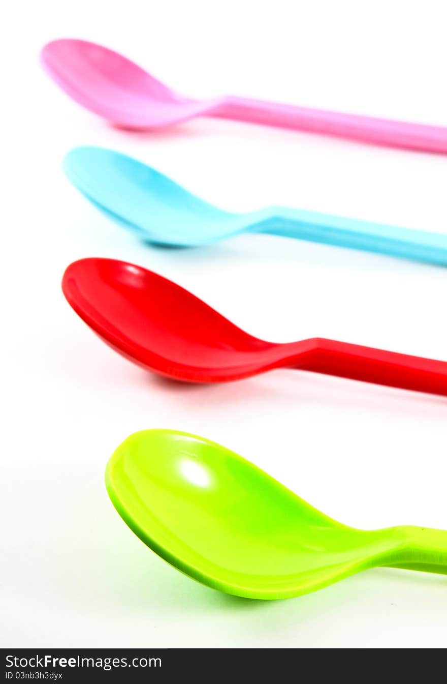 Colorful plastic spoons on white background