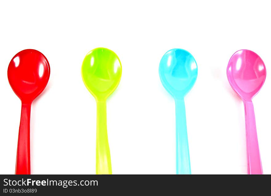 Colorful plastic spoons on white background