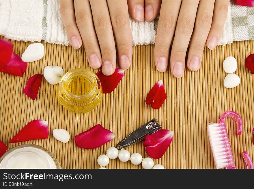 Close-up of girl lying on hand towel next to the cream, rose petals and manicure equipment. Close-up of girl lying on hand towel next to the cream, rose petals and manicure equipment