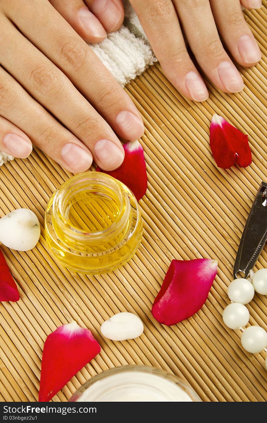 Close-up of girl lying on hand towel next to the cream, rose petals and manicure equipment. Close-up of girl lying on hand towel next to the cream, rose petals and manicure equipment