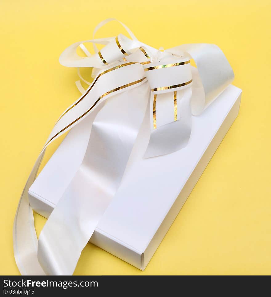 Gift box with bow over yellow background