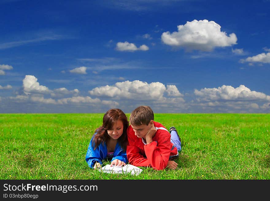 Two teenagers studying outdoors on grass