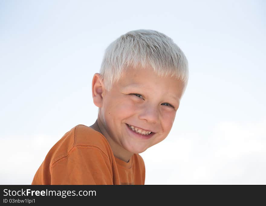 Young blonde boy in orange shirt, laughs. Young blonde boy in orange shirt, laughs