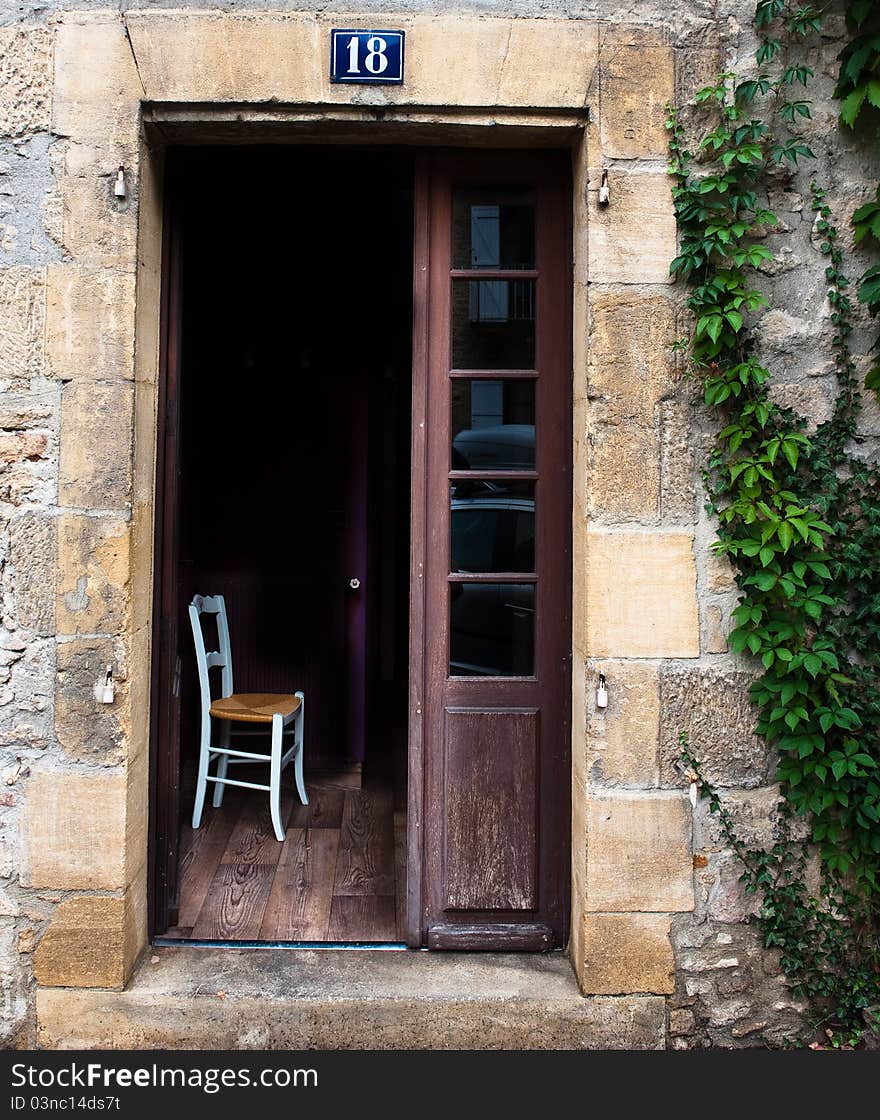 Single chair in an open doorway of a old French buildiing. Single chair in an open doorway of a old French buildiing