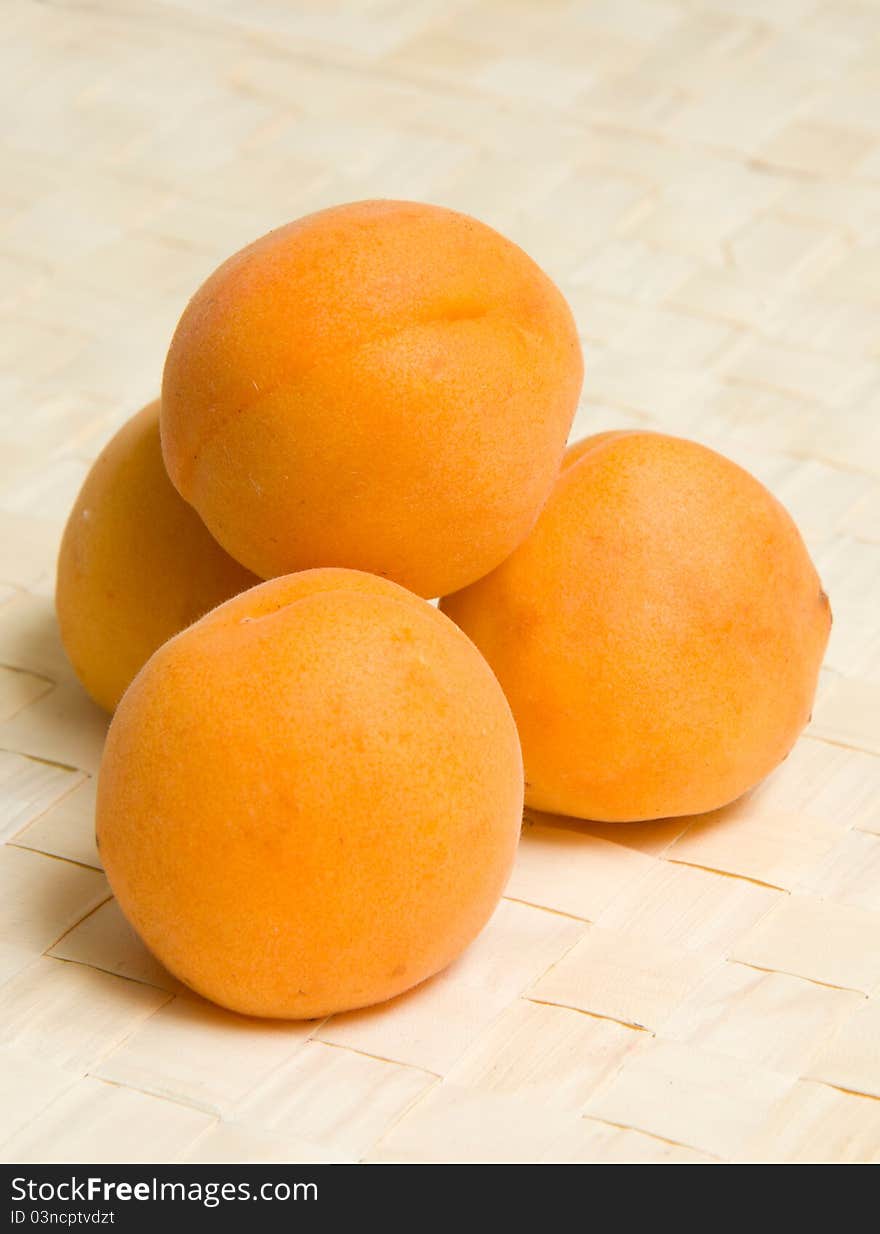 Four apricots on wicker table