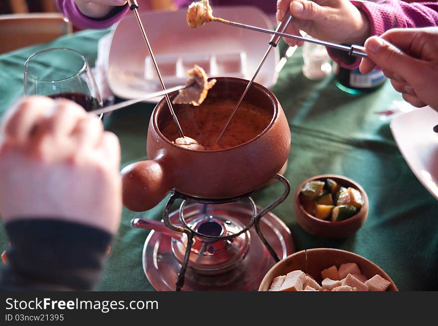 People serving pieces of vegetables and jam in a bowl of fondeau in a restaurant of a winter center of sky in Chile. People serving pieces of vegetables and jam in a bowl of fondeau in a restaurant of a winter center of sky in Chile.