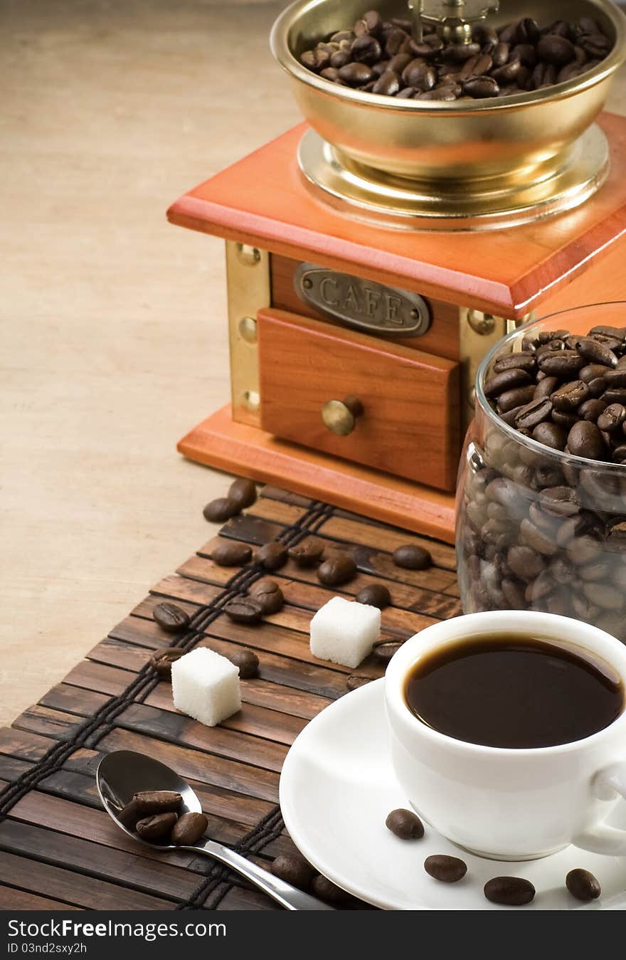 Cup of coffee, grinder and jar full of beans on wood