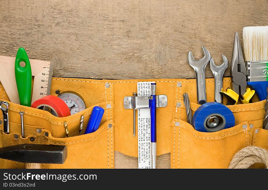 Set of tools in belt on wooden texture