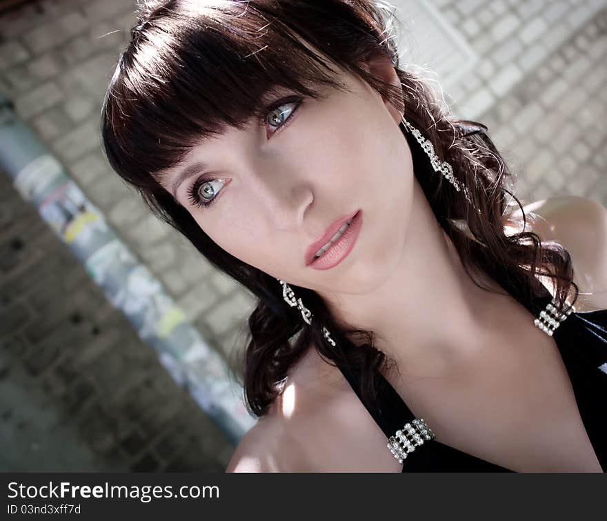 Beautiful young brunette girl poses in front of brick panted wall. Beautiful young brunette girl poses in front of brick panted wall